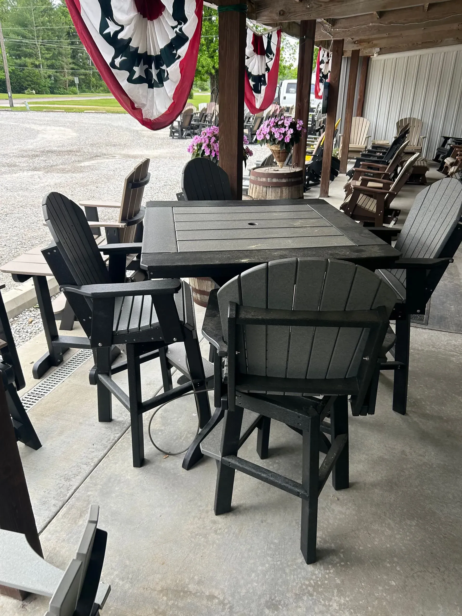 Outdoor patio table with four black chairs under a wooden awning, American flag decor.