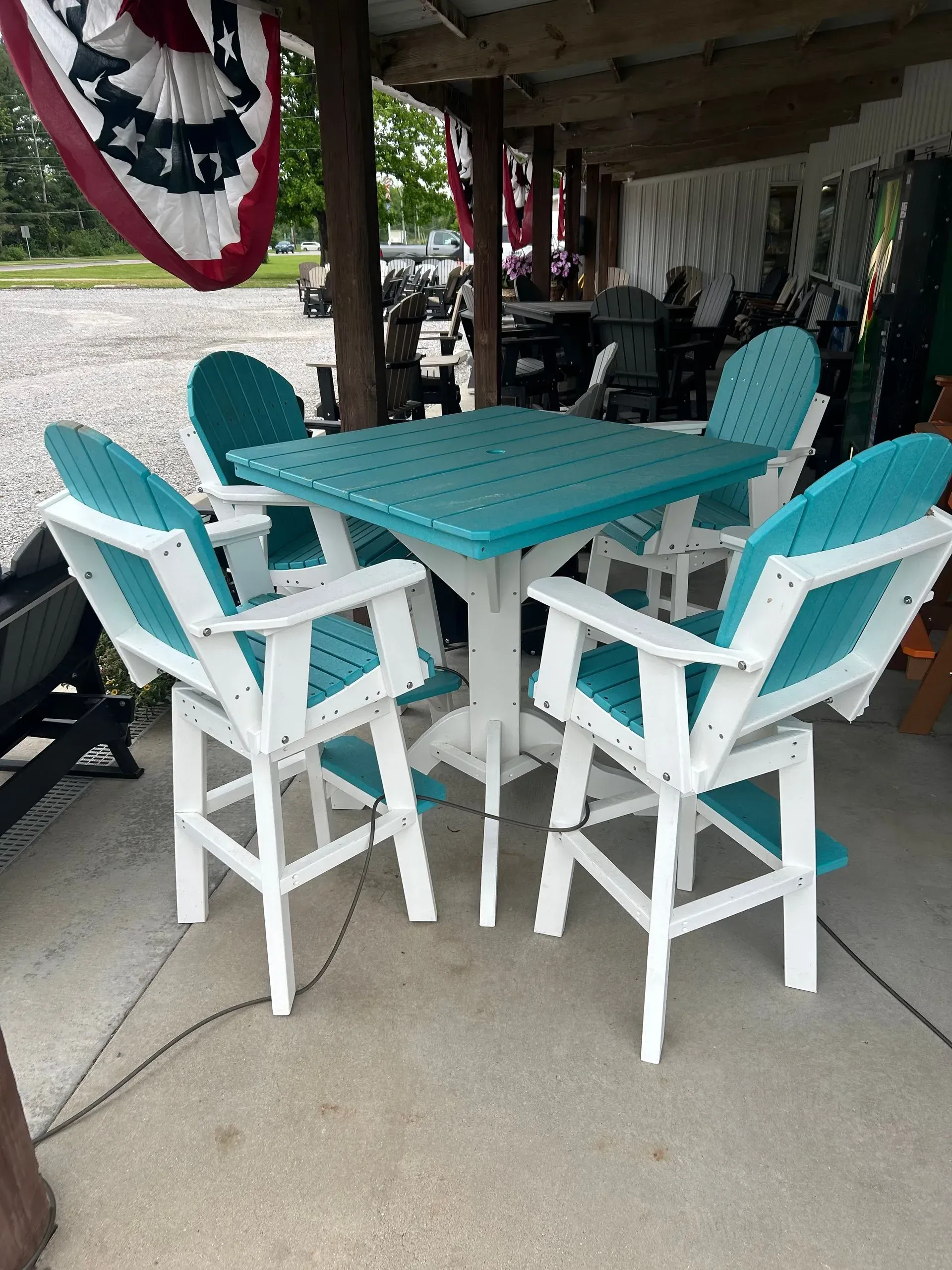 Outdoor teal and white bar height table and chairs on a porch.