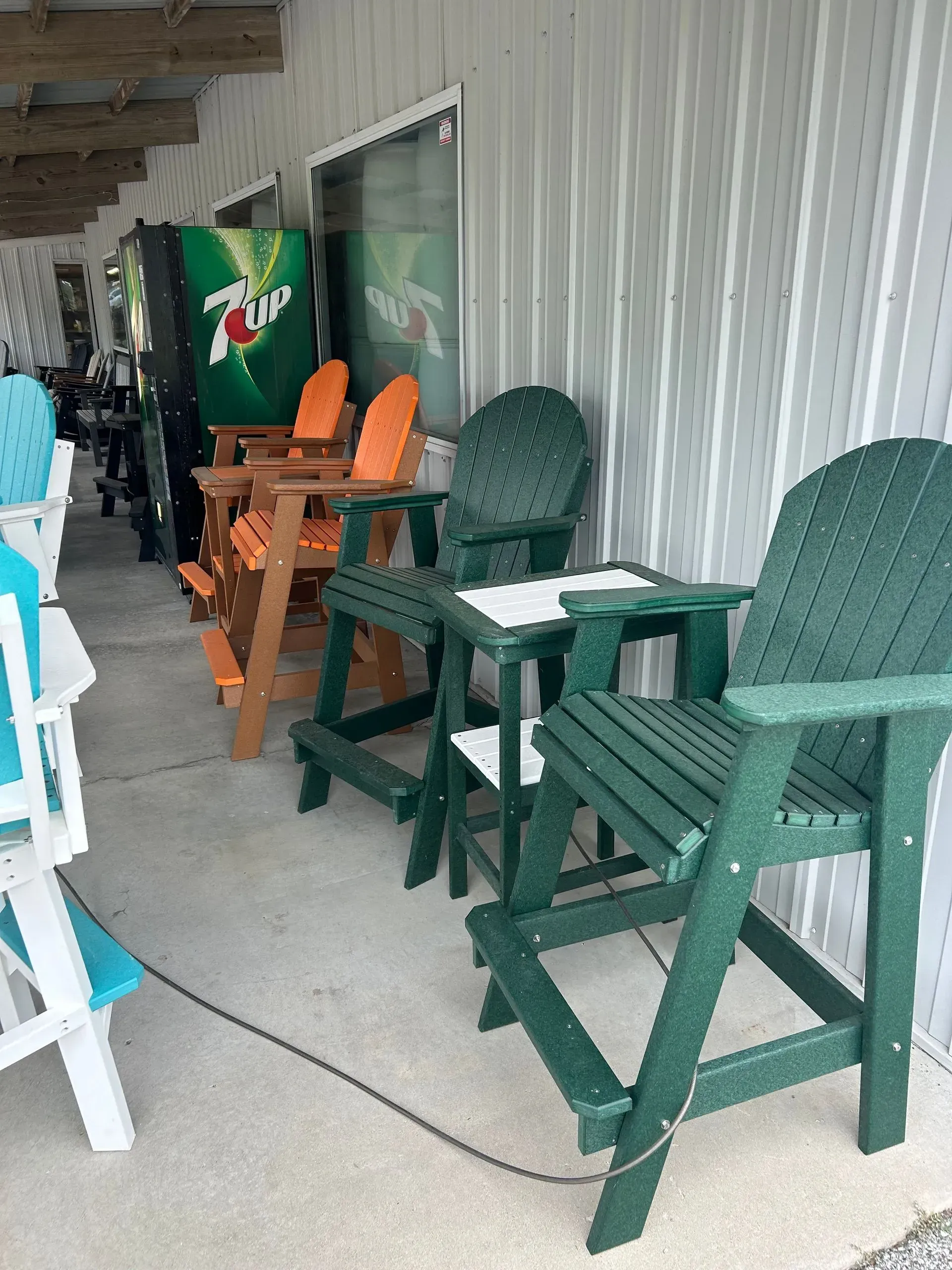 Outdoor Adirondack chairs in various colors displayed outside a store under a corrugated metal roof.
