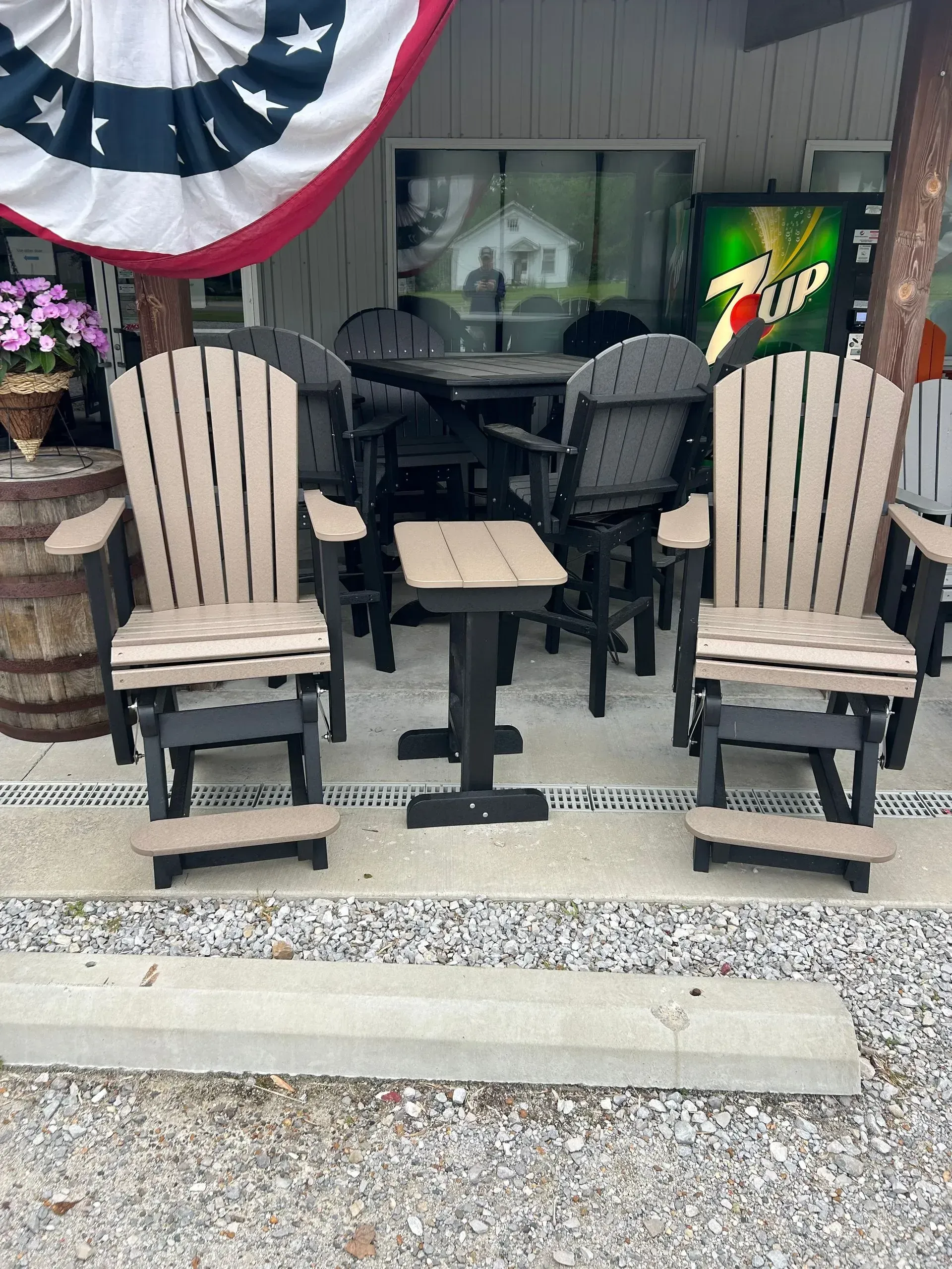 Two tan and black rocking chairs with a small table in front, outdoor setting.