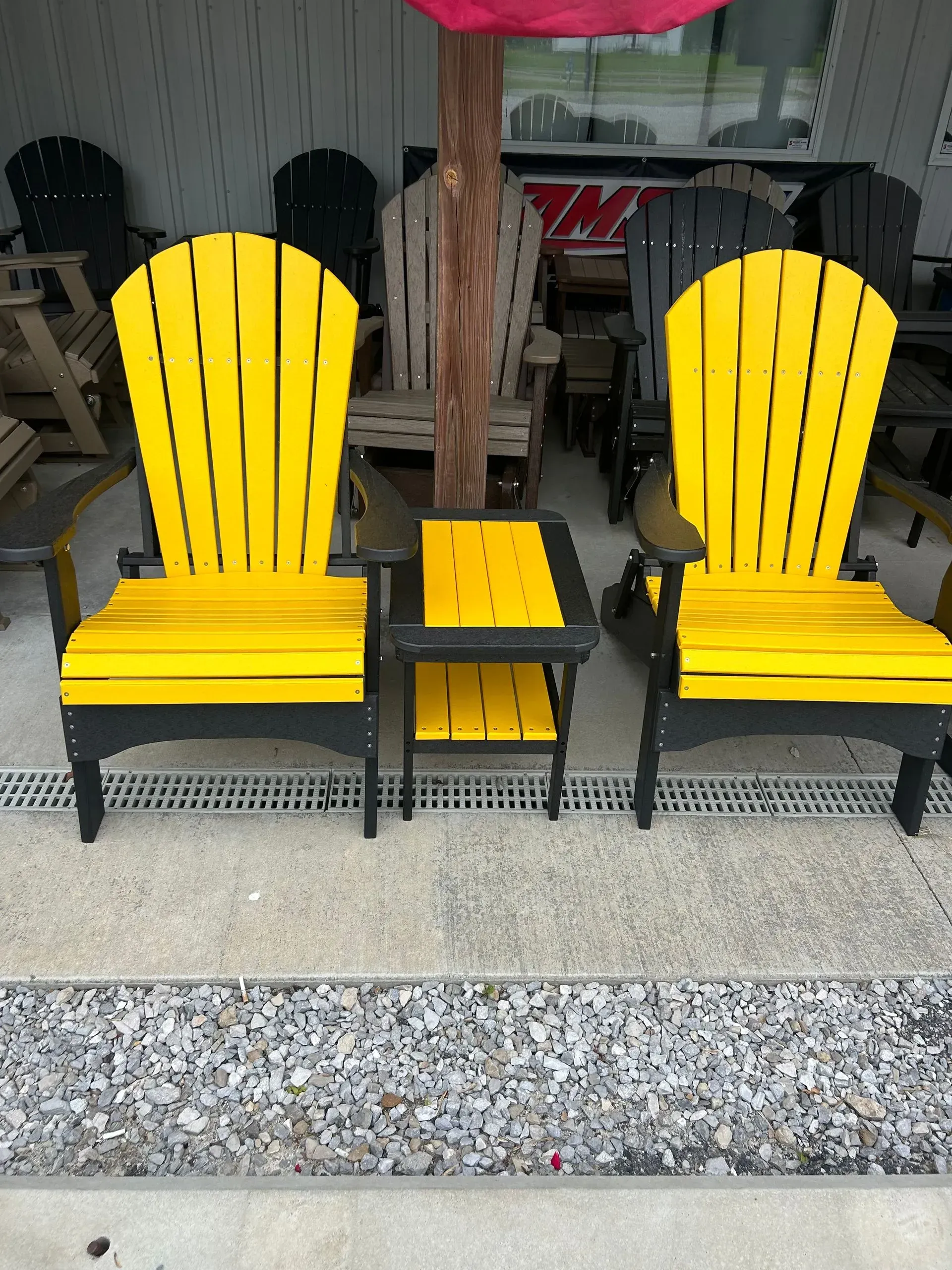 Two yellow Adirondack chairs and a small table on a gravel patio.