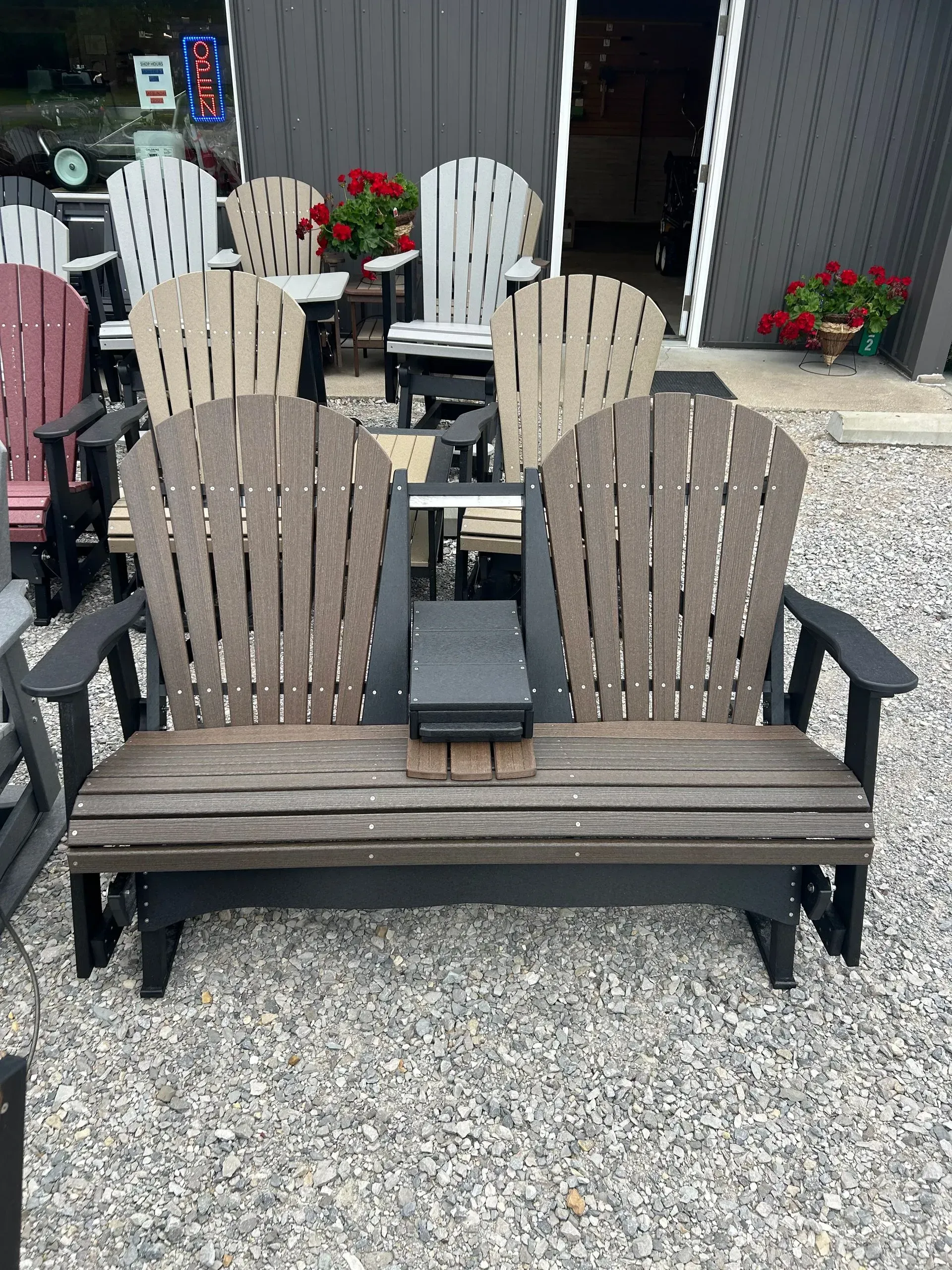 Double Adirondack glider bench in brown and black, with built-in center console, outside store.
