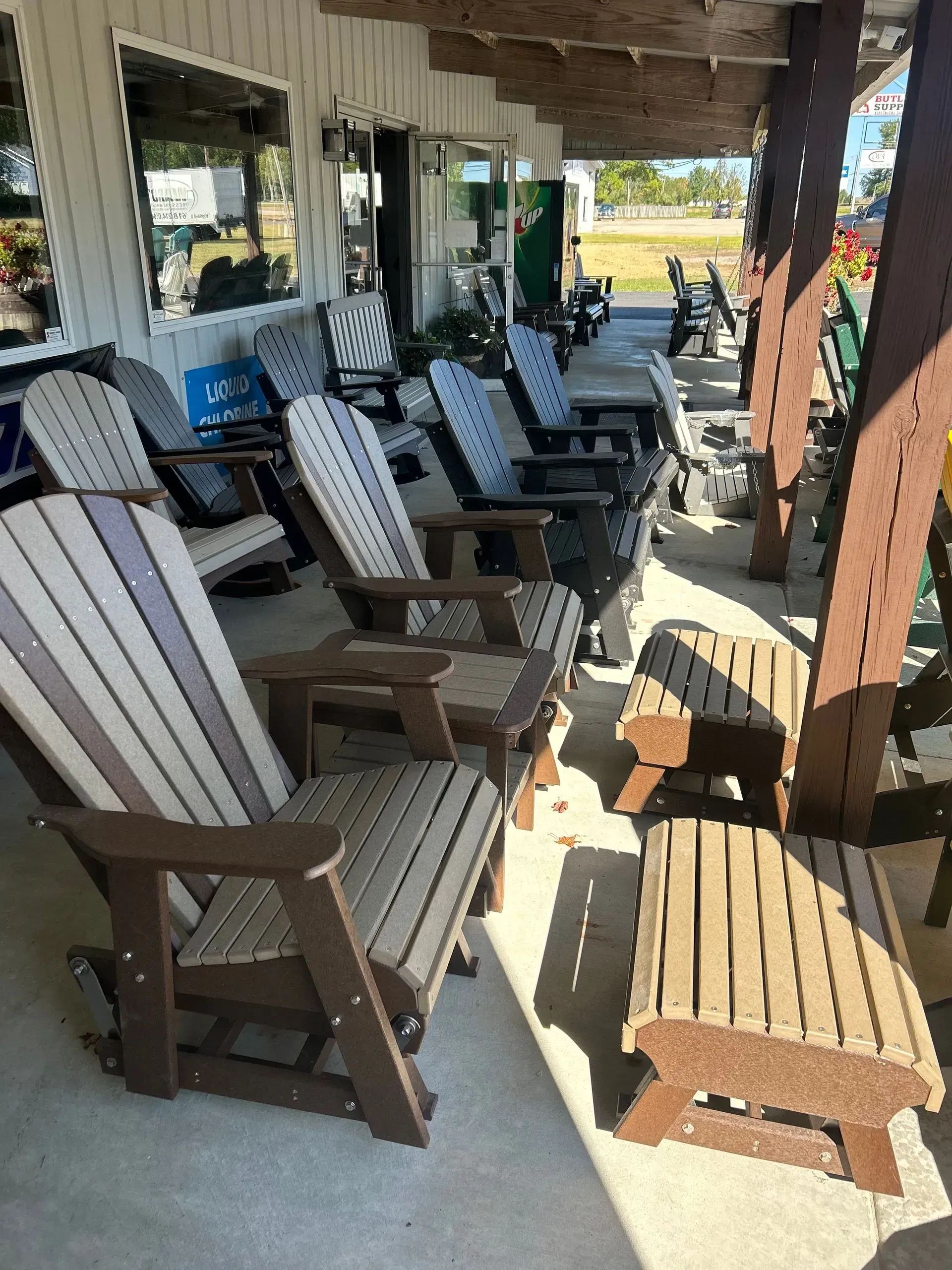 Outdoor furniture display with Adirondack chairs in various colors, under a covered patio.
