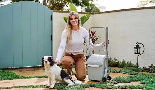 A woman is kneeling down next to a small dog.