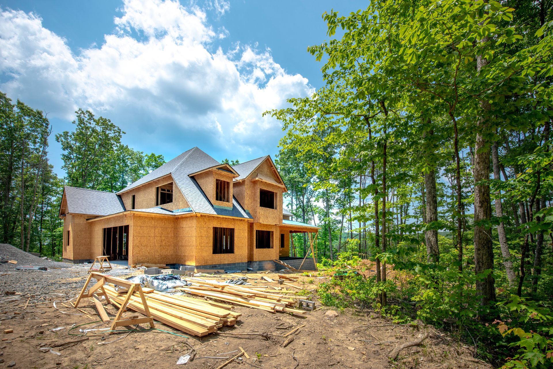 A large wooden house is being built in the middle of a forest.