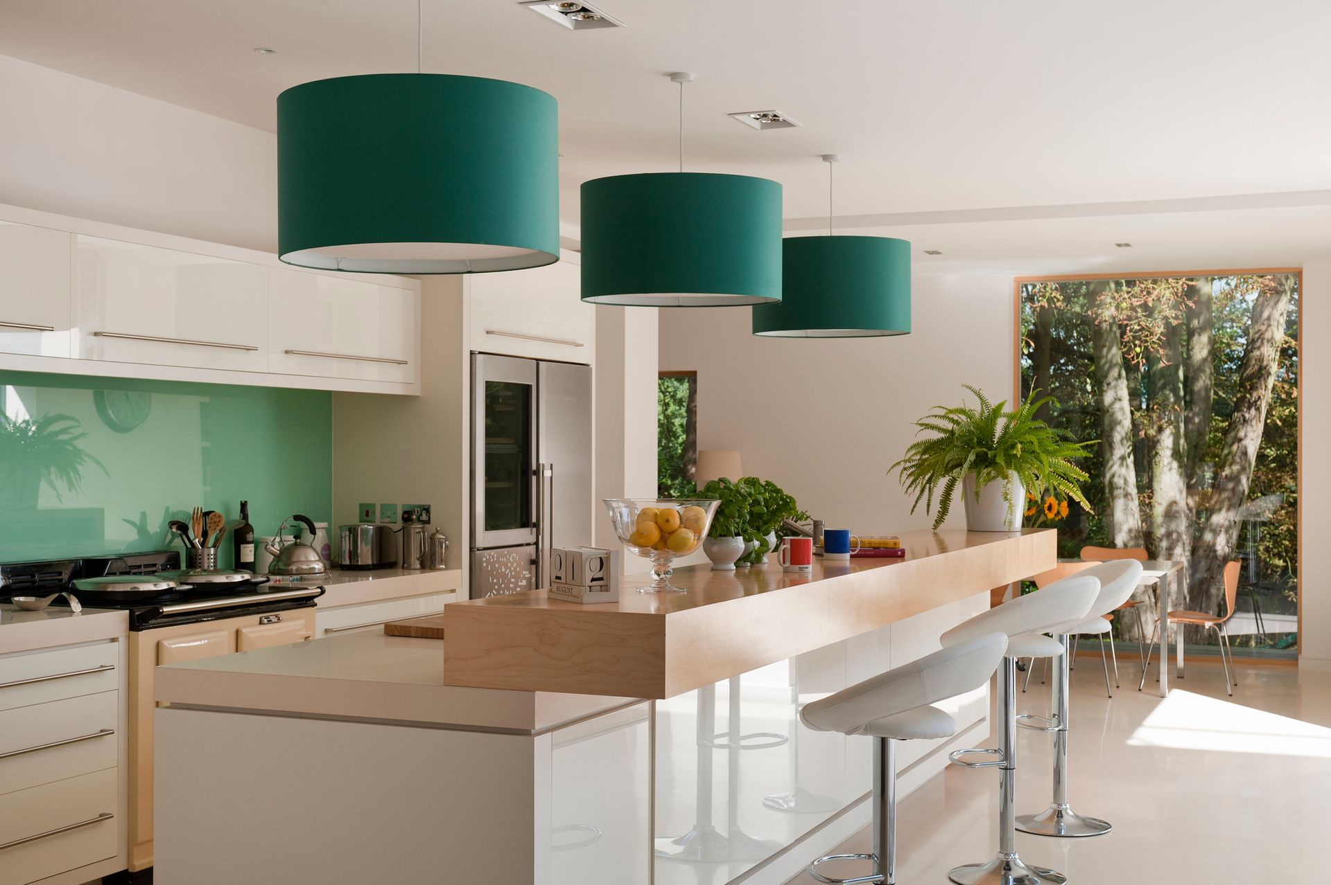 A kitchen with green lamps hanging from the ceiling