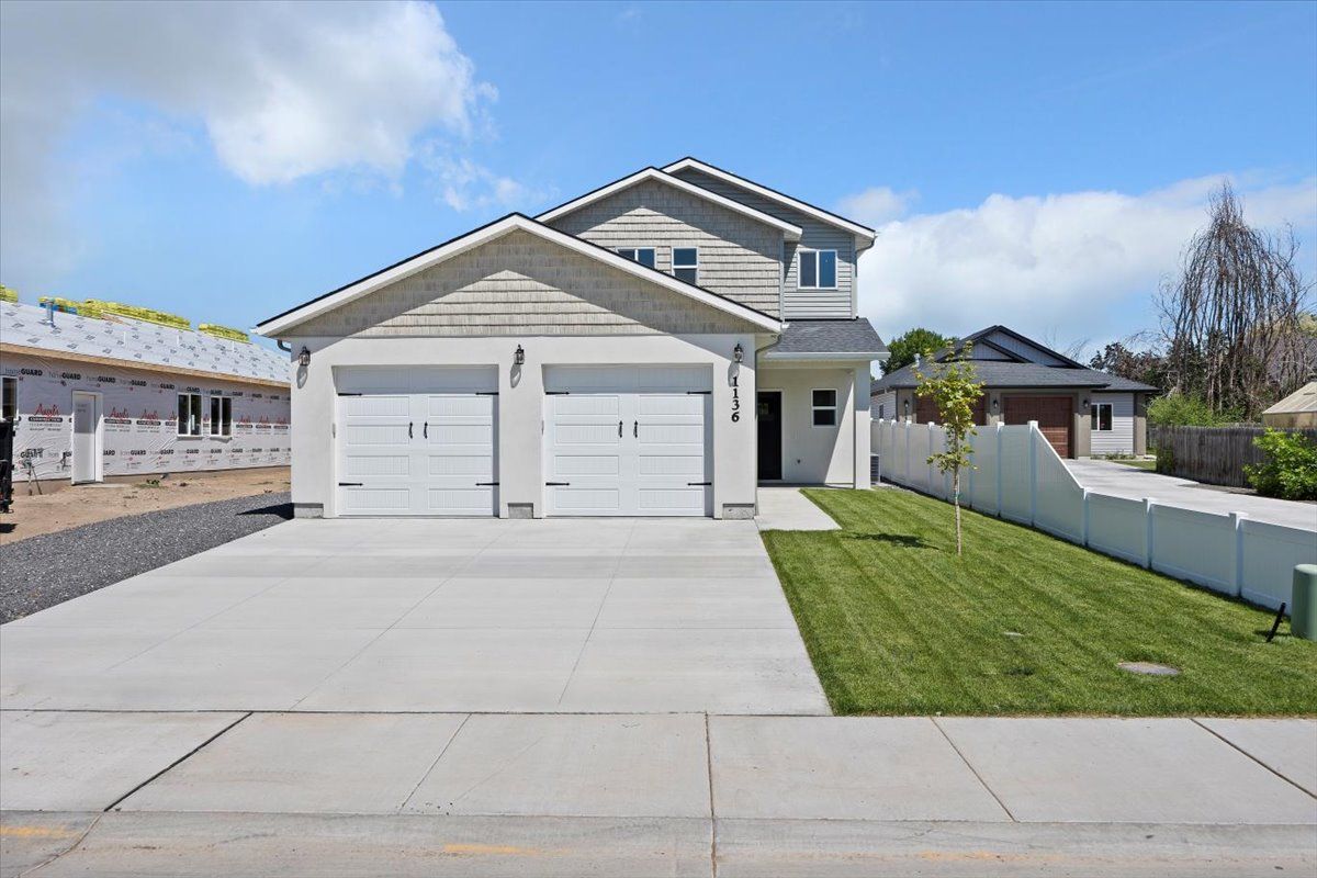 Two-story house with a two-car garage, blue sky, and green lawn. Concrete driveway.