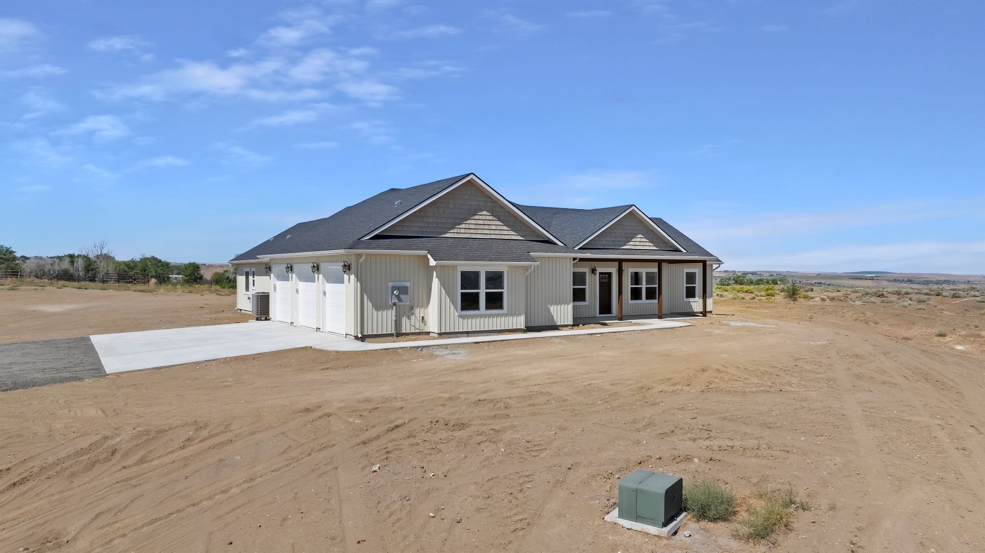 New house under construction on a dirt lot with a blue sky.