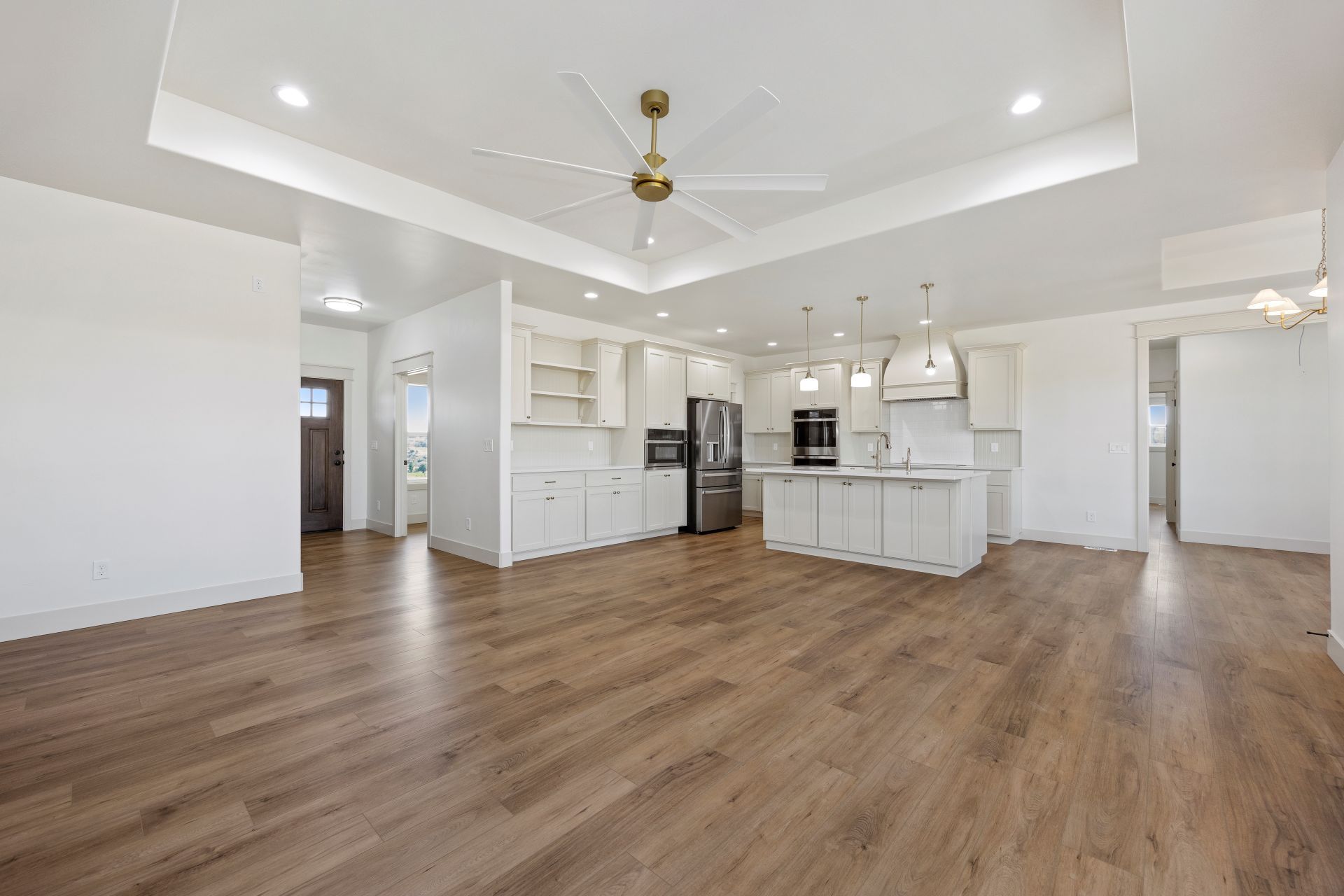Spacious open-concept kitchen and living area with hardwood floors, white cabinets, and stainless steel appliances.