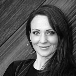 A woman wearing hoop earrings is smiling in a black and white photo.
