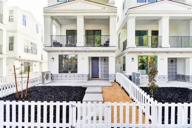 A white house with a white picket fence in front of it.