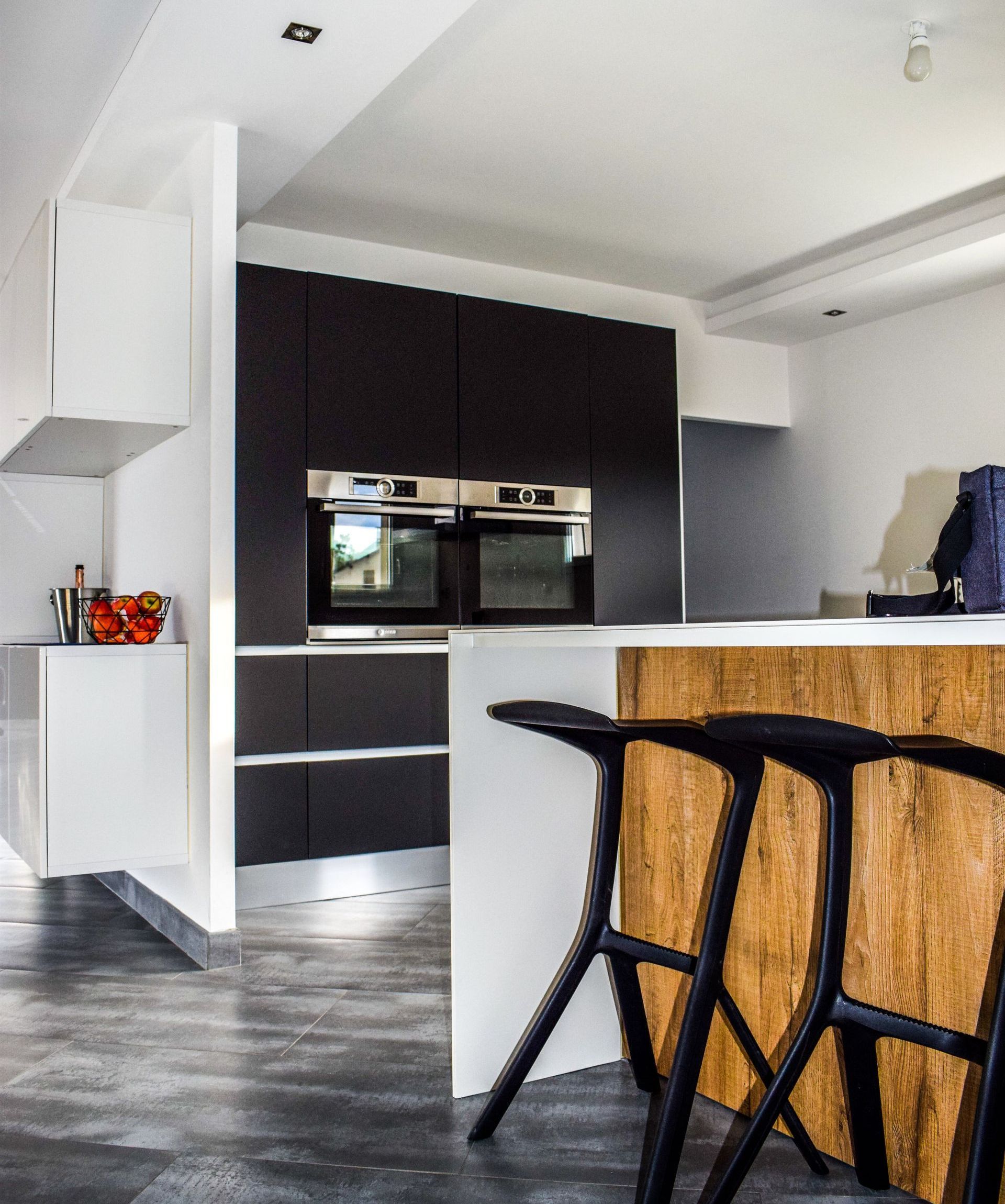 A kitchen with black stools and a wooden counter