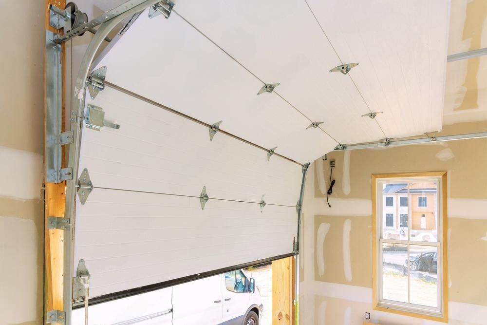 A white van is parked in a garage with a garage door open.