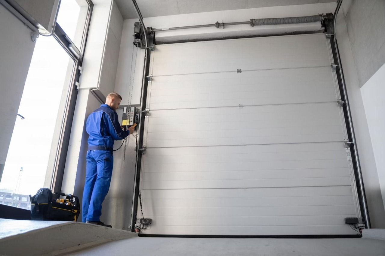 A man is working on a garage door in a garage.