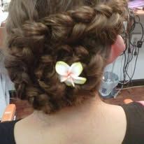 A person's head with a braided hairstyle and a white and yellow flower hair accessory.