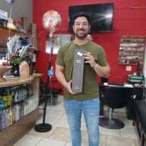 Man holding a bottle, standing in a shop with shelves of products and a balloon.