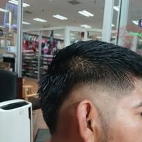 Close-up of a person's head with a fade haircut; indoors with lights visible.