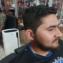 Man with a short haircut, in a barber shop, looking to the side.
