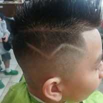 Close-up of a person's head with a designed haircut. The hair is short, with a faded side and a line design.