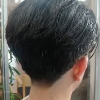 A person's head, viewed from the back, with short, dark hair and a neatly trimmed neckline.