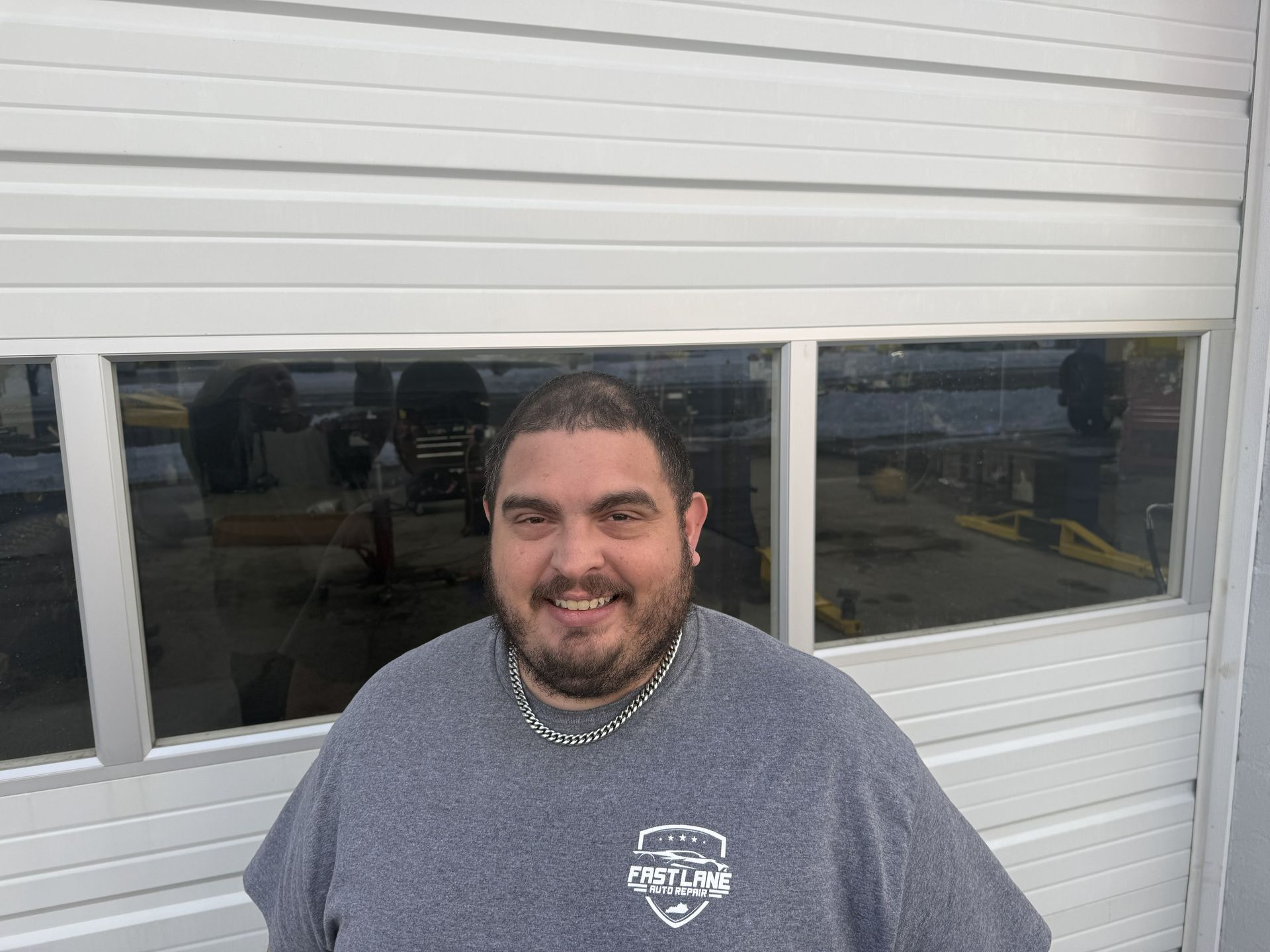 Man smiling in front of a white garage door with a glass window and interior reflection.