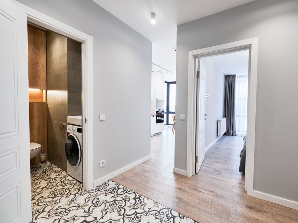 A hallway in a house with a washing machine and a toilet.