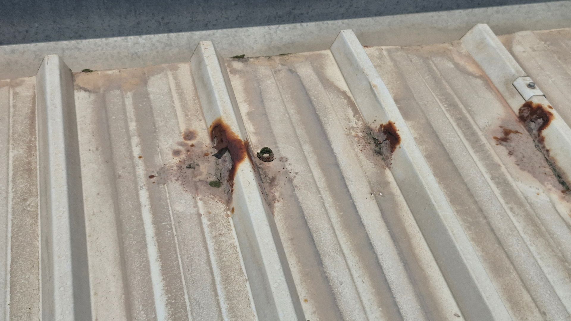 Corrugated metal roof with rust stains around bolts.