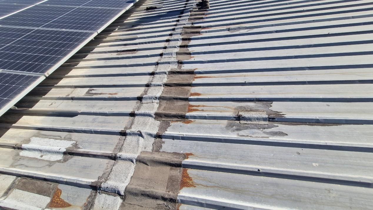 Metal roof with visible repairs and solar panels.