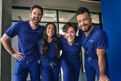 A group of people wearing blue scrubs are posing for a picture.