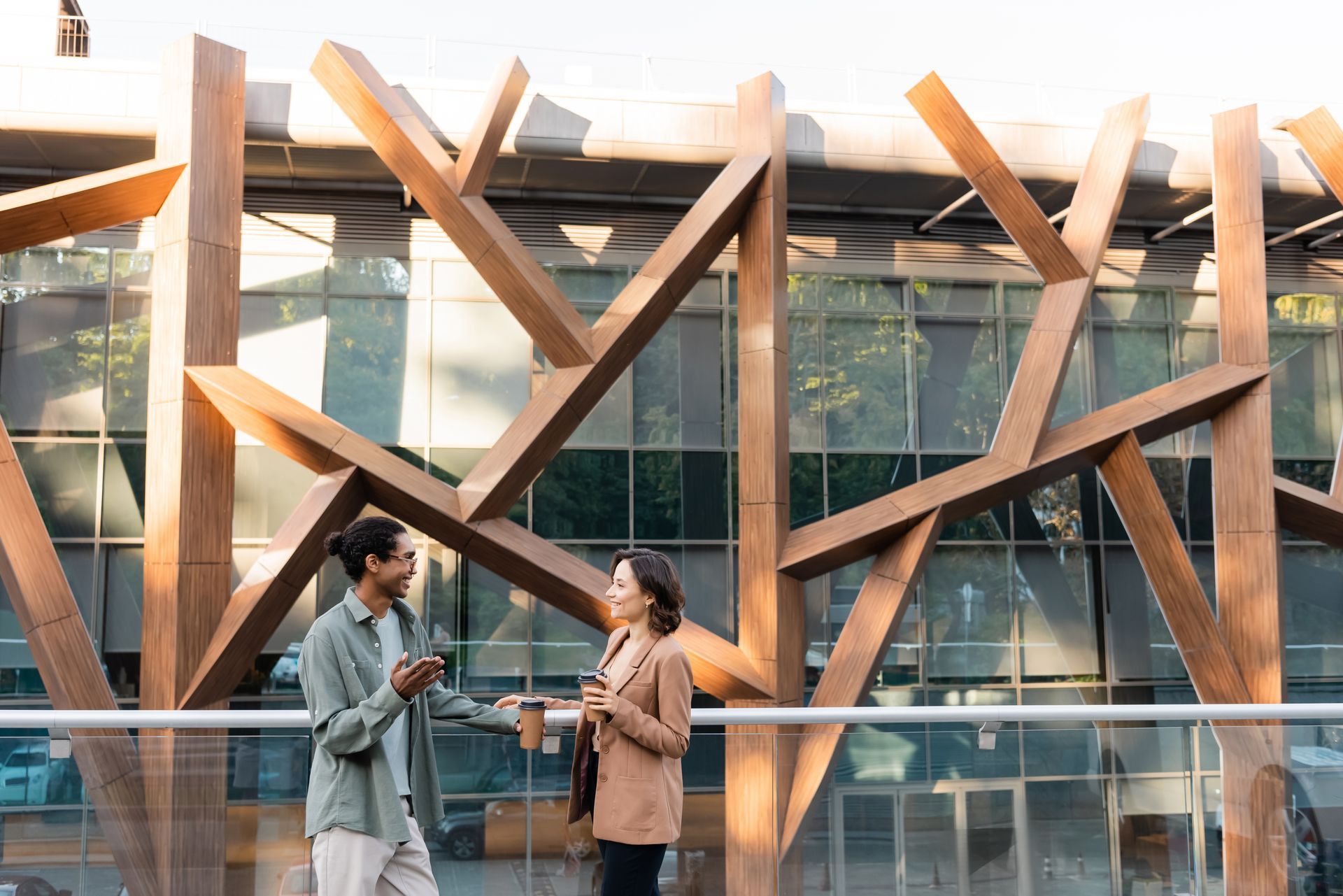 A man and a woman are standing in front of a building talking to each other.