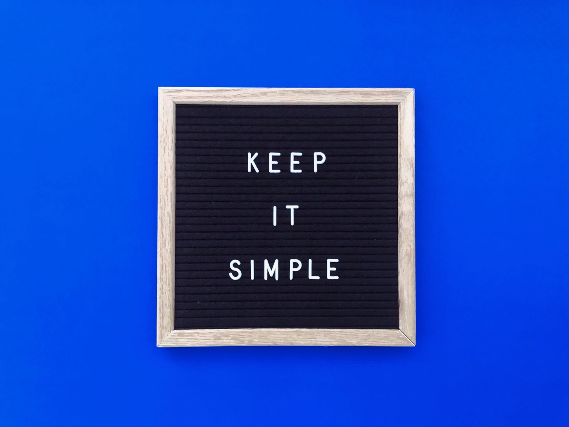 A black letter board with the words `` keep it simple '' on a blue background.