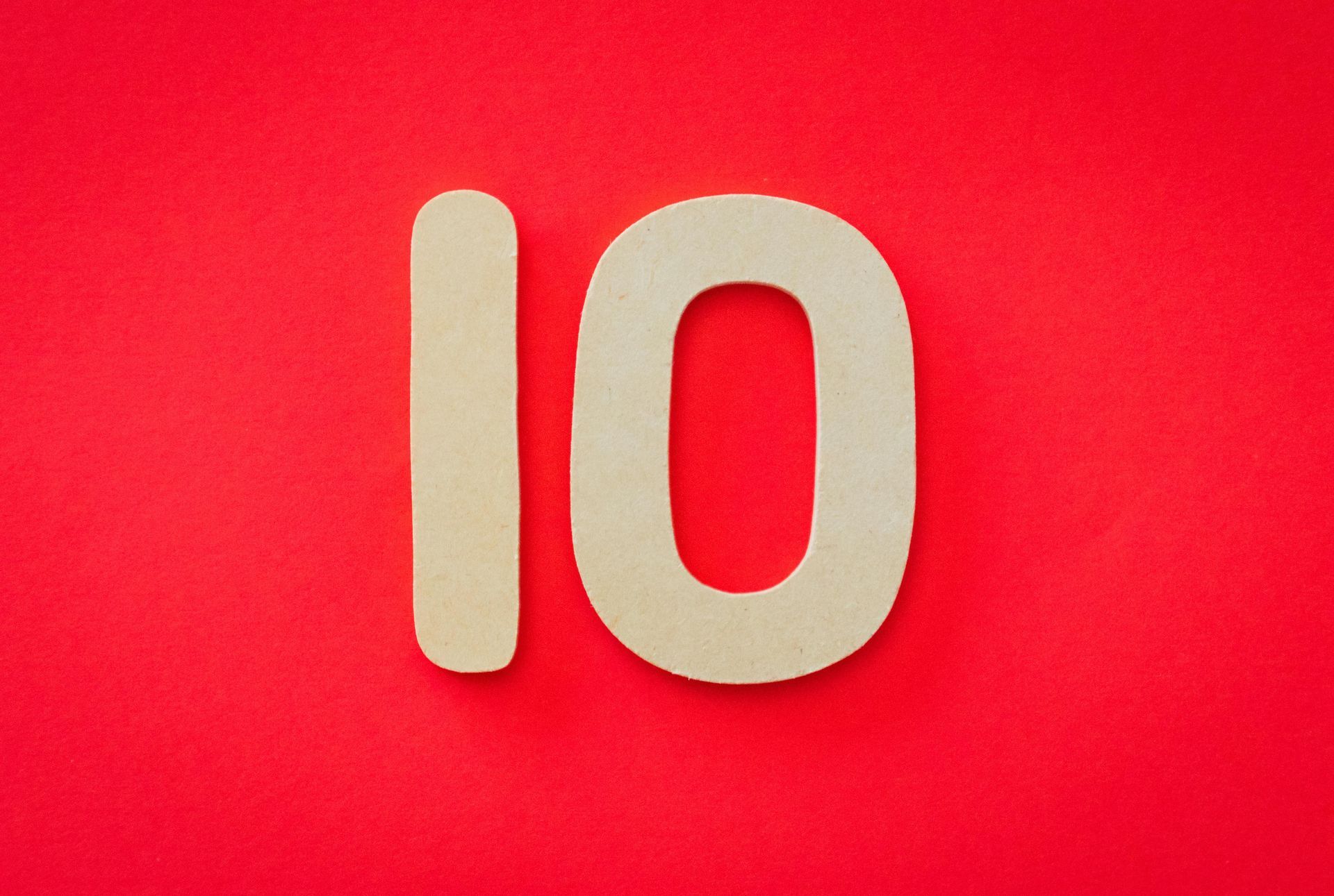 The number 10 is cut out of paper on a red background.