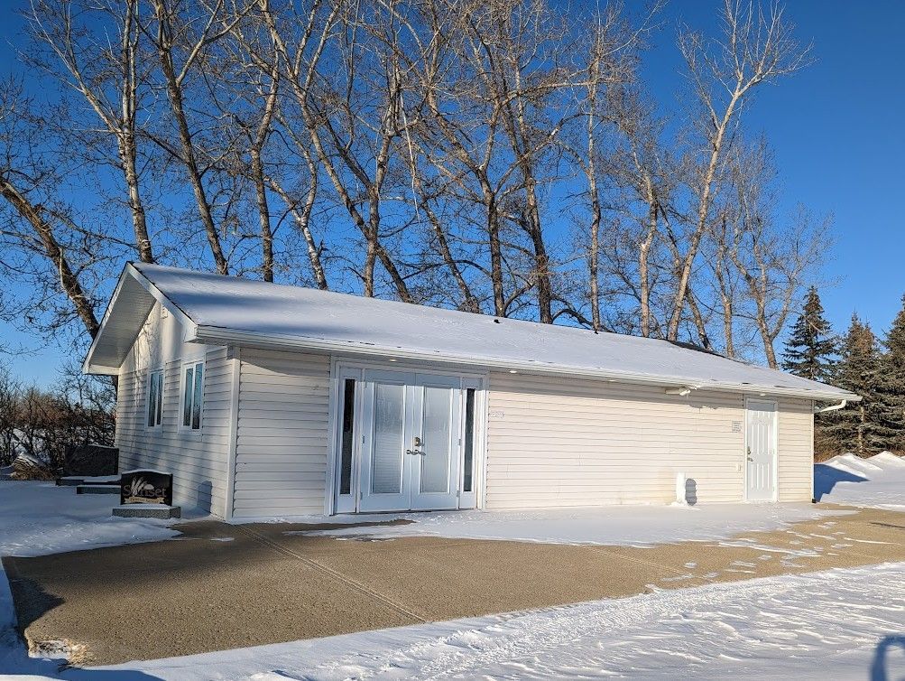 White building covered in snow, with double doors and concrete pad in a snowy setting.