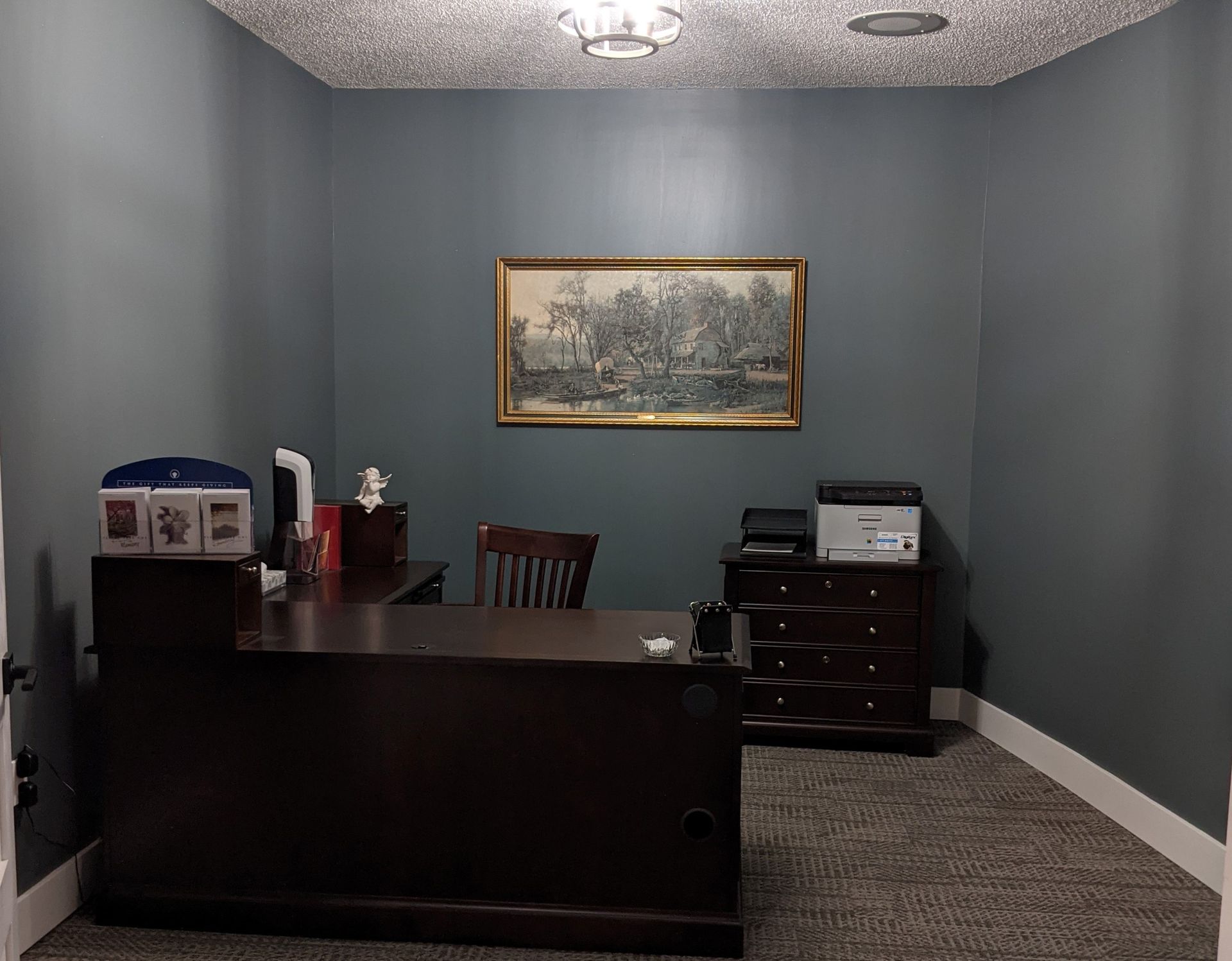 Office with dark wood desk, gray walls, and framed artwork.