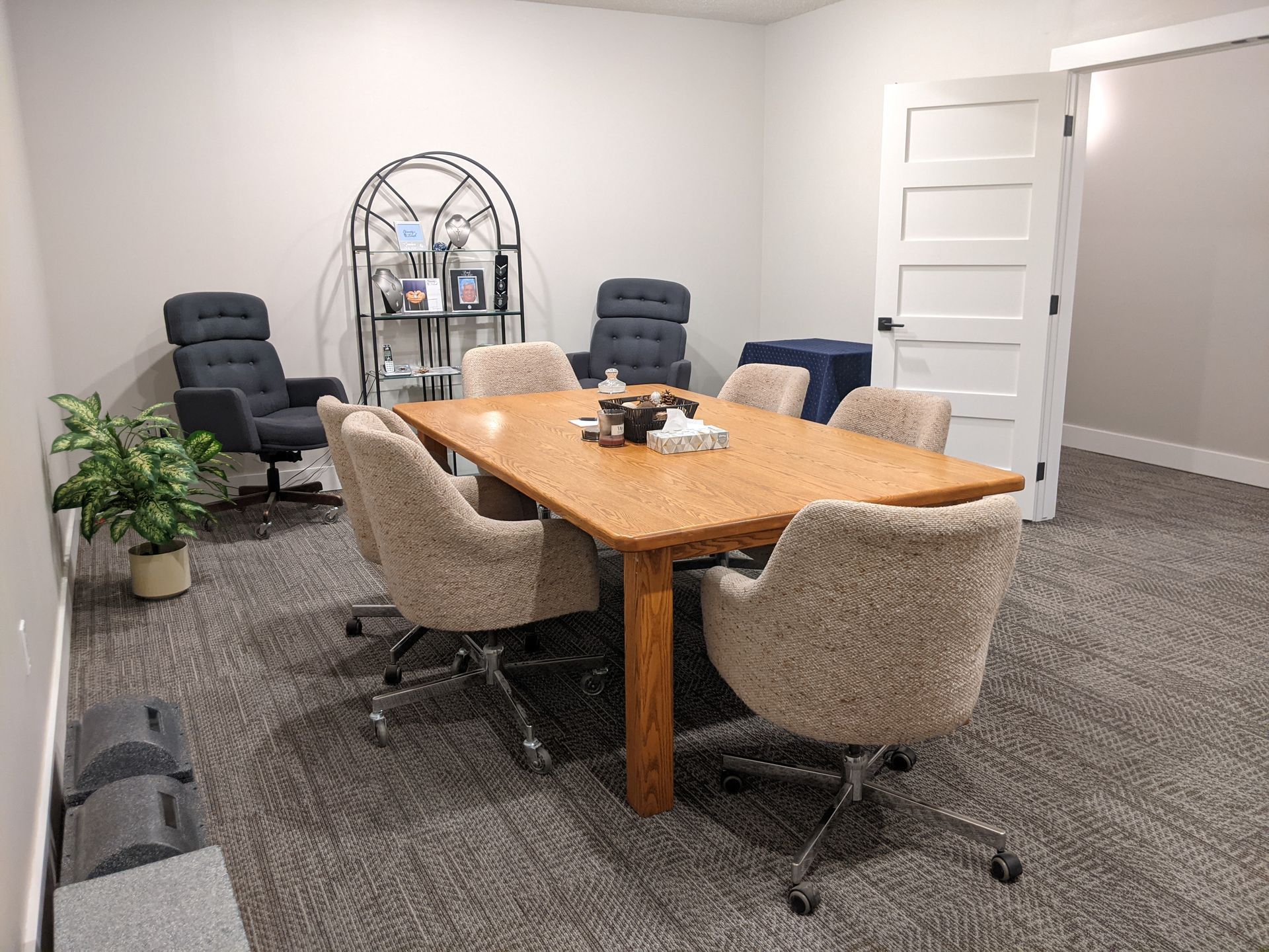 Meeting room with wooden table, eight chairs, and a small plant.
