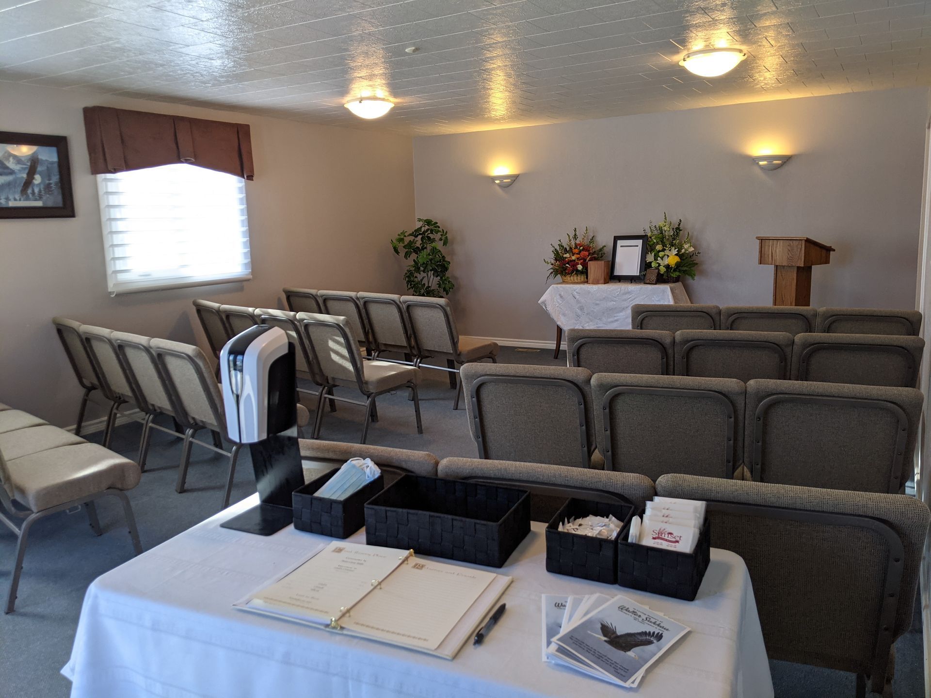 Interior of a funeral home chapel with chairs, a table with guest book, and a podium.