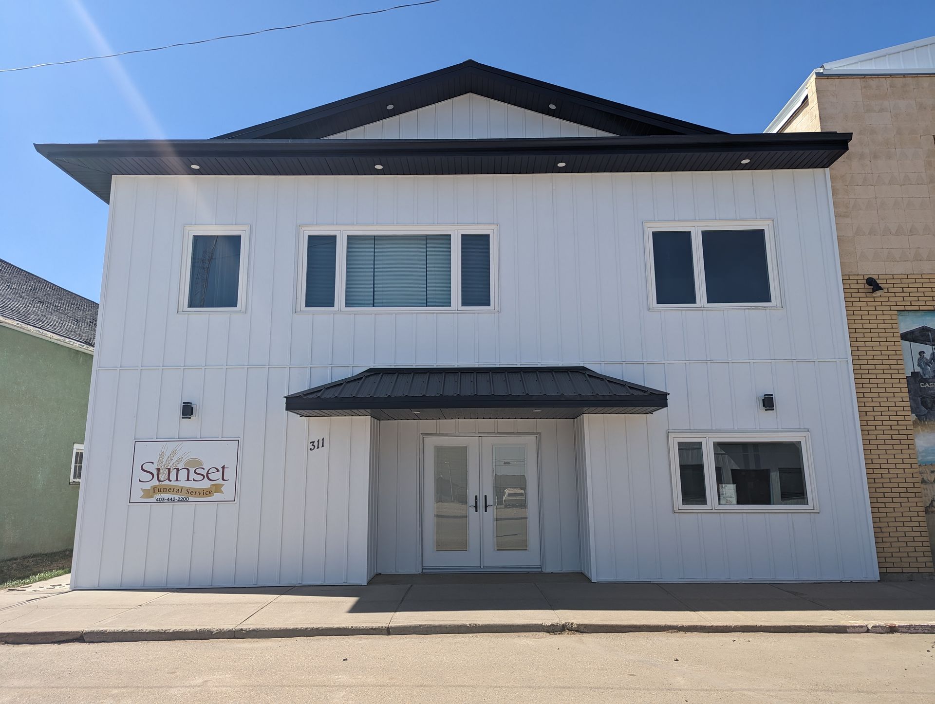 White two-story building with black roof, sign reading 