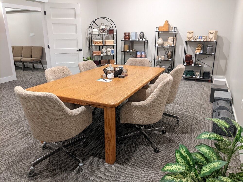 Conference room with wooden table and chairs, display shelves, and a waiting area visible.