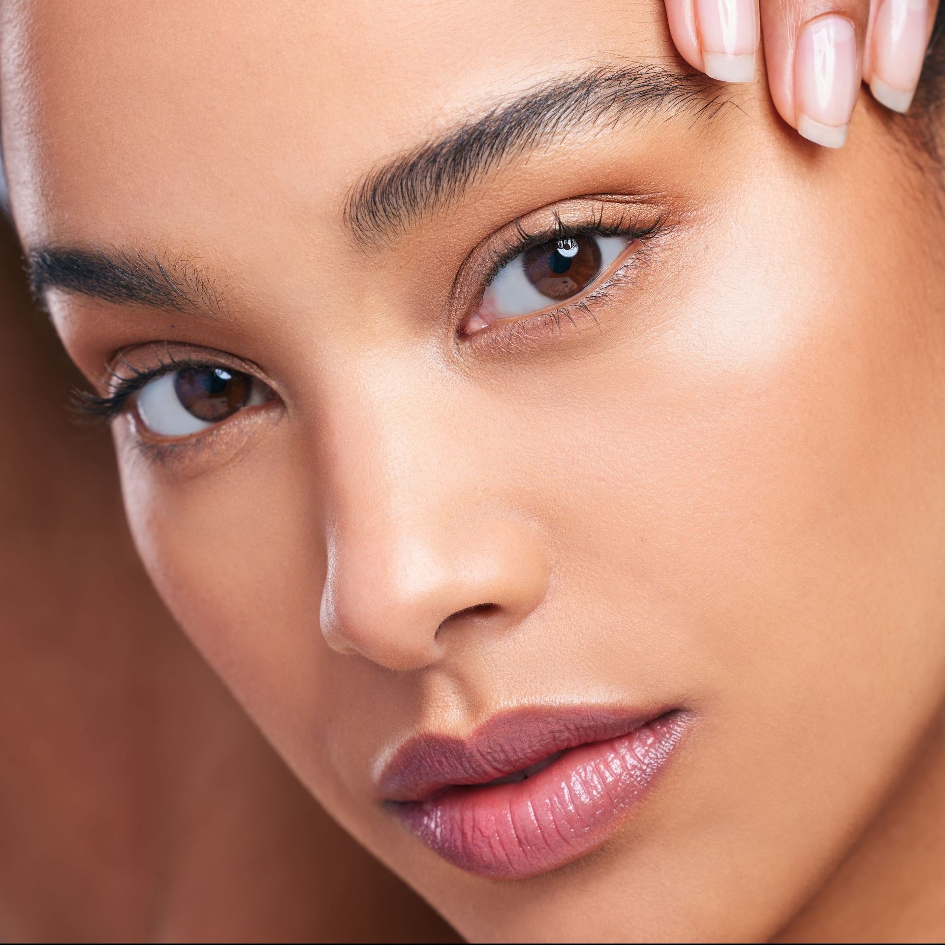 A close up of a woman 's face with her hand on her forehead.