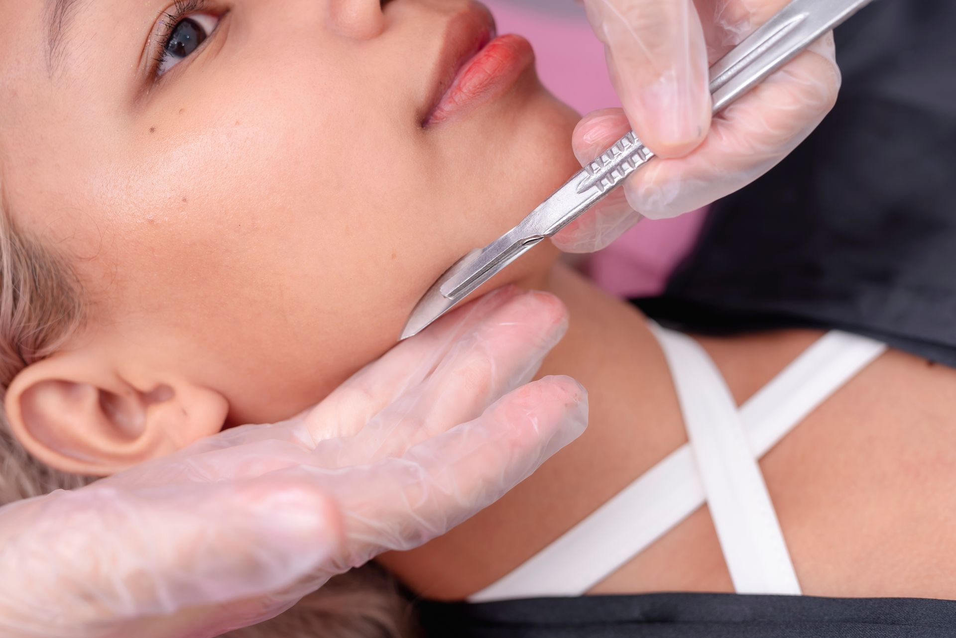 A woman is getting her face shaved with a razor.