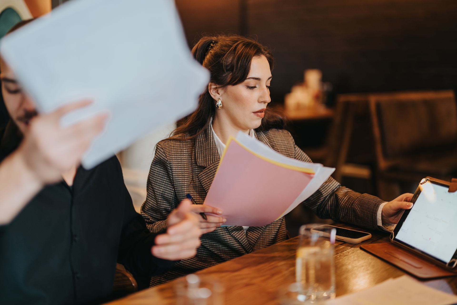 Two people reviewing documents and a tablet at a table in a cafe.