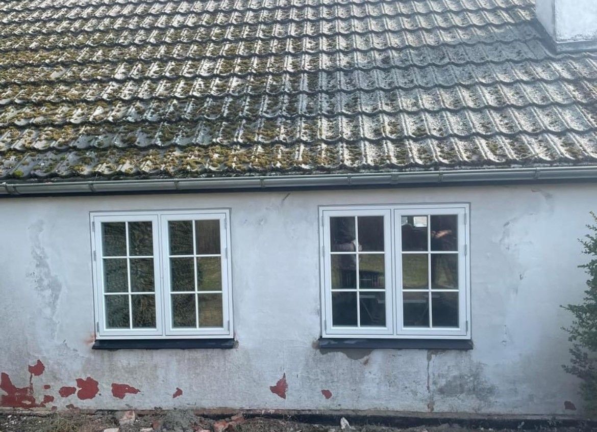 Et hvidt hus med tegltag og to vinduer