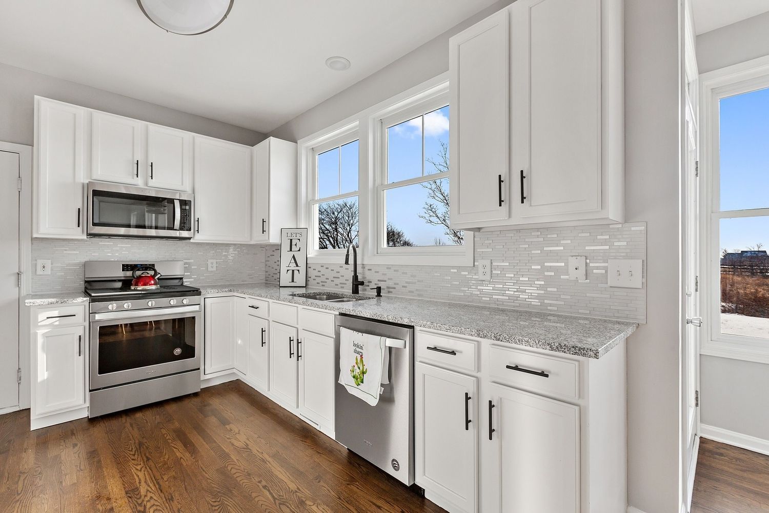 White kitchen with stainless steel appliances, white cabinets, and granite countertops.