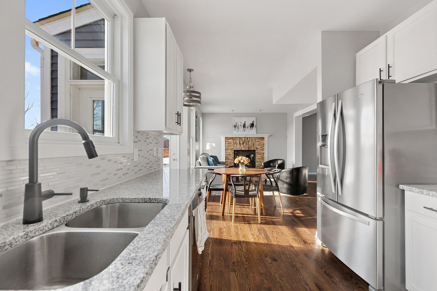 Kitchen with granite countertops, stainless steel sink and appliances, open to dining area and living room with fireplace.