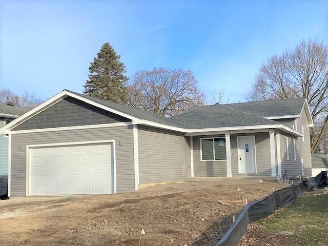 Gray house with a white garage door and front door, under a partly cloudy sky.