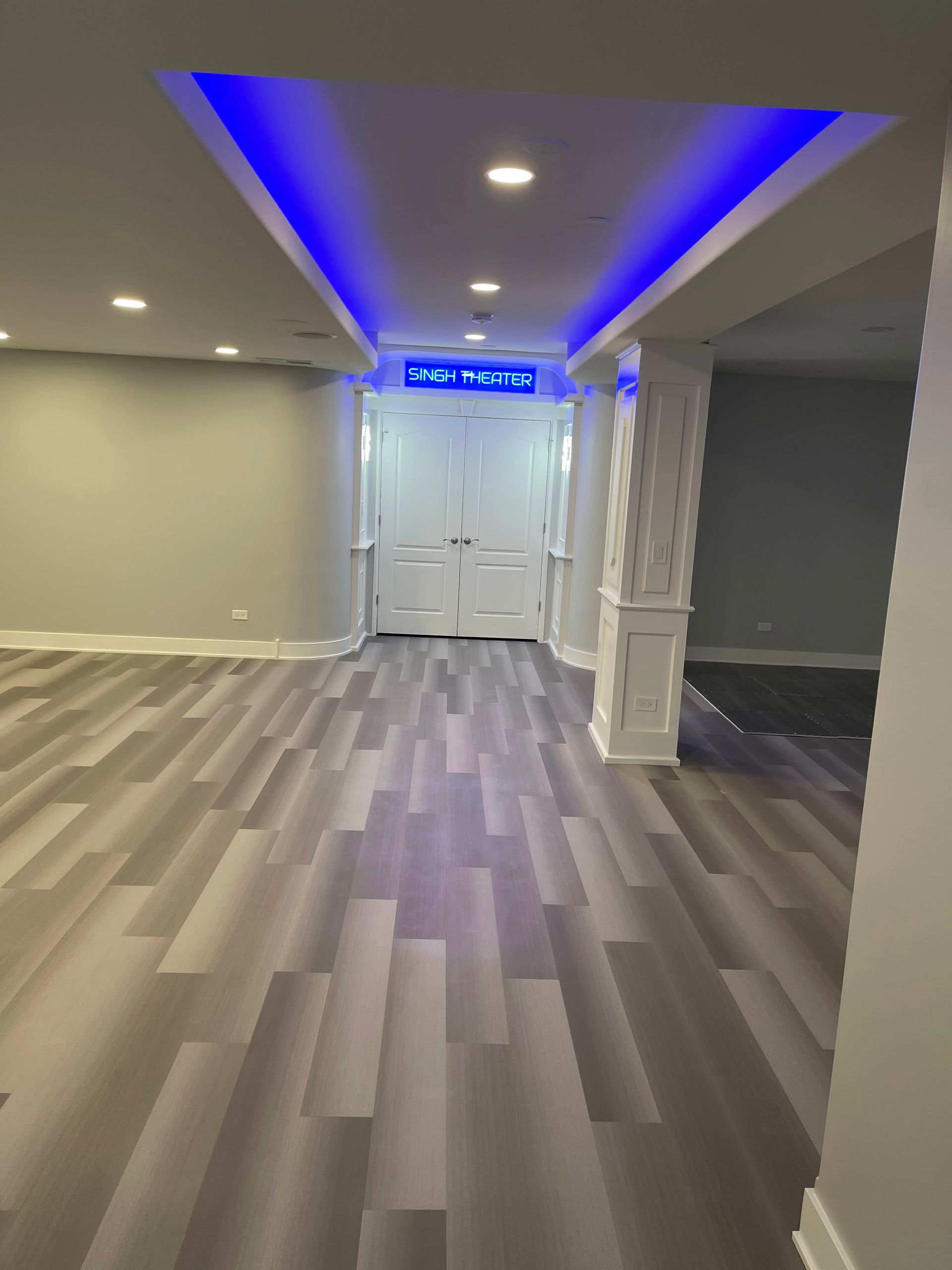 Interior view of a finished basement with hardwood floors, gray walls, recessed lighting on the ceiling.