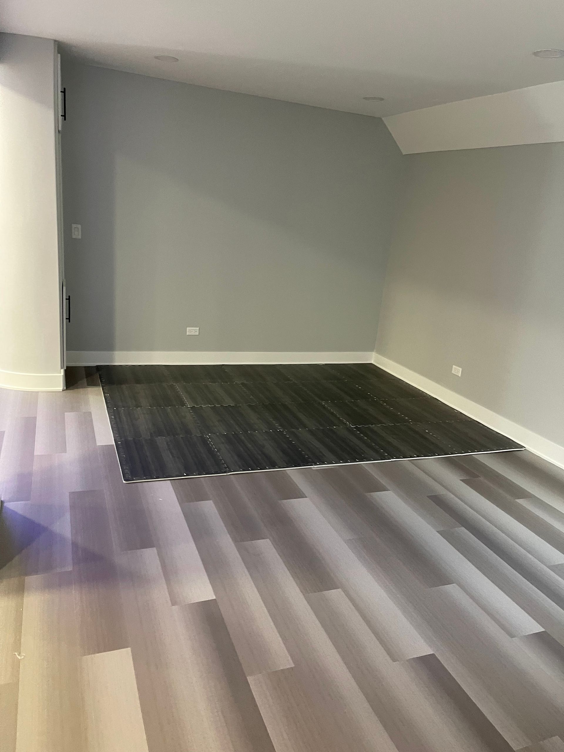 Room with gray walls, partially completed dark wood floor, and existing light wood floor.