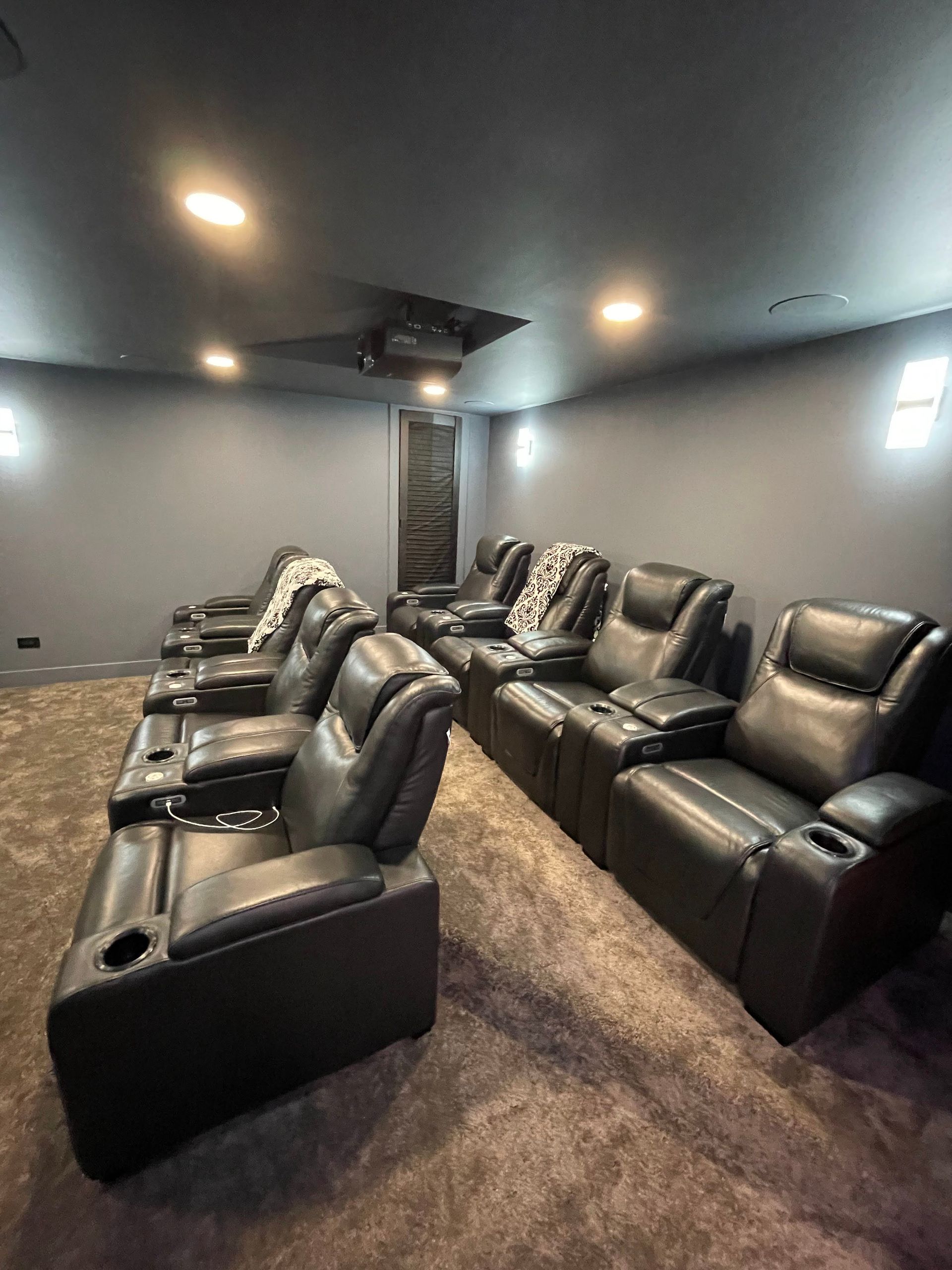 Black leather theater recliners in a dark gray home theater room.