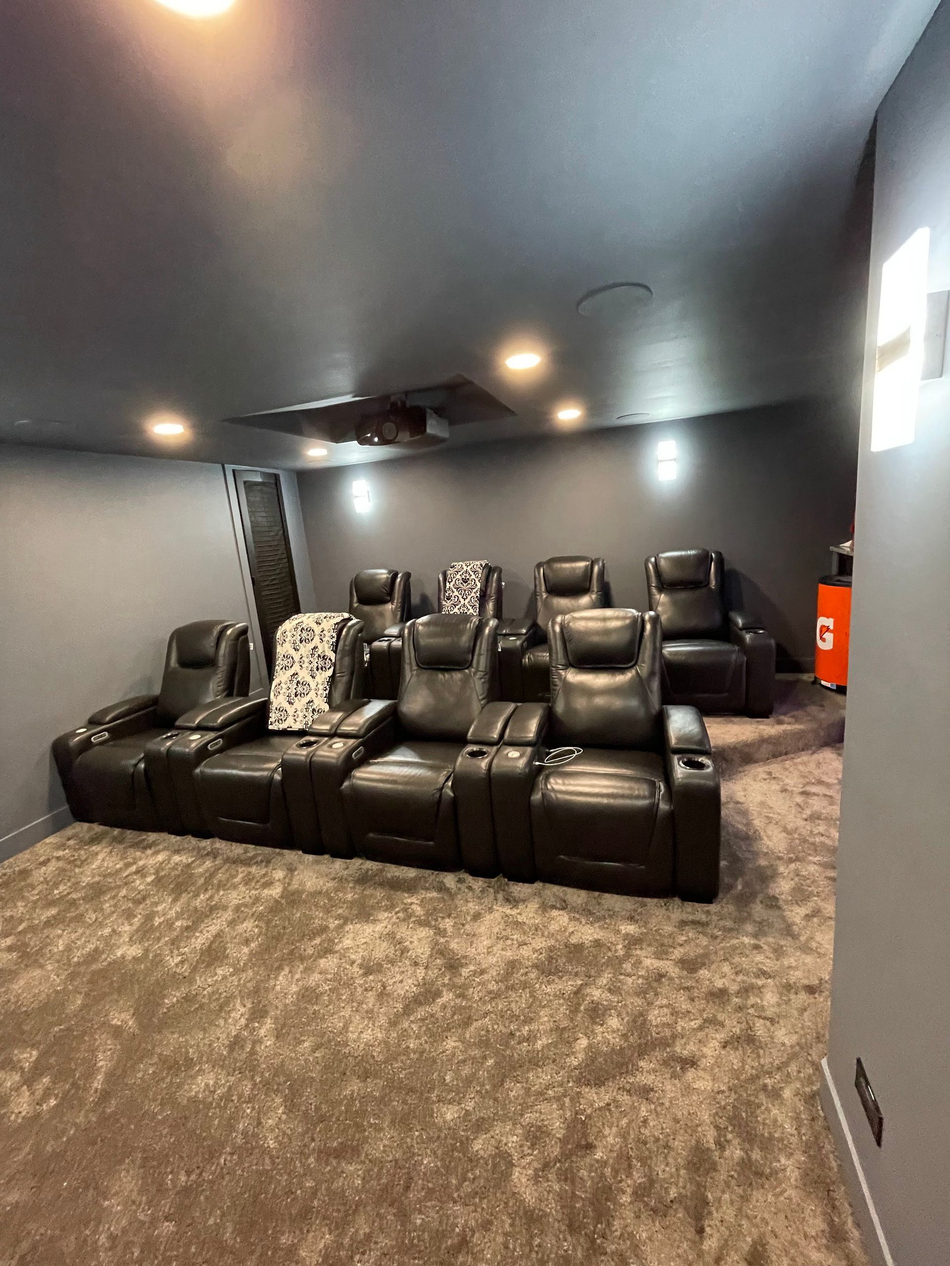 Home theater with black leather recliners, gray walls, and shaggy carpet.