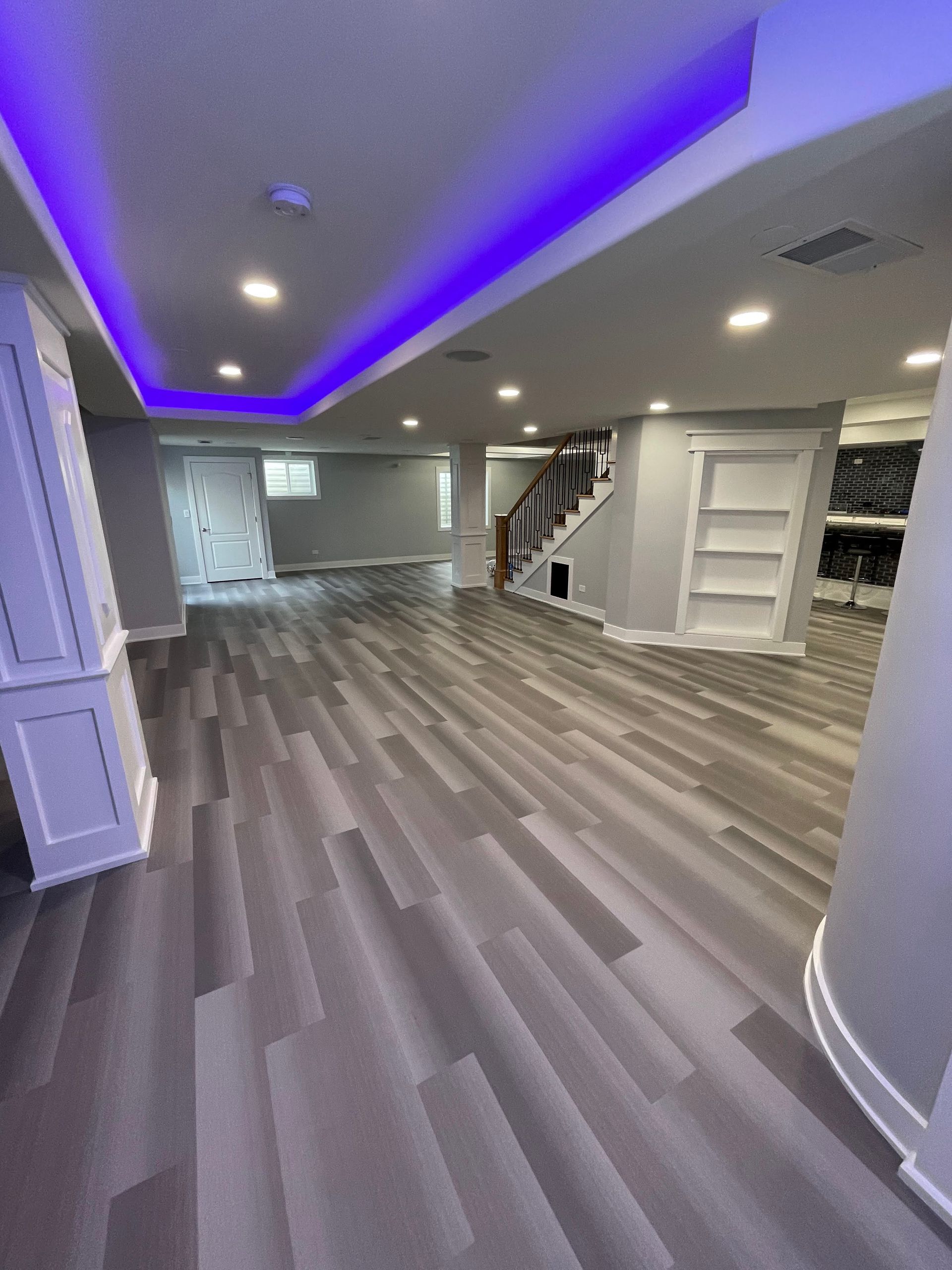 Finished basement with gray wood-look floors, recessed lighting, and purple ceiling lights.